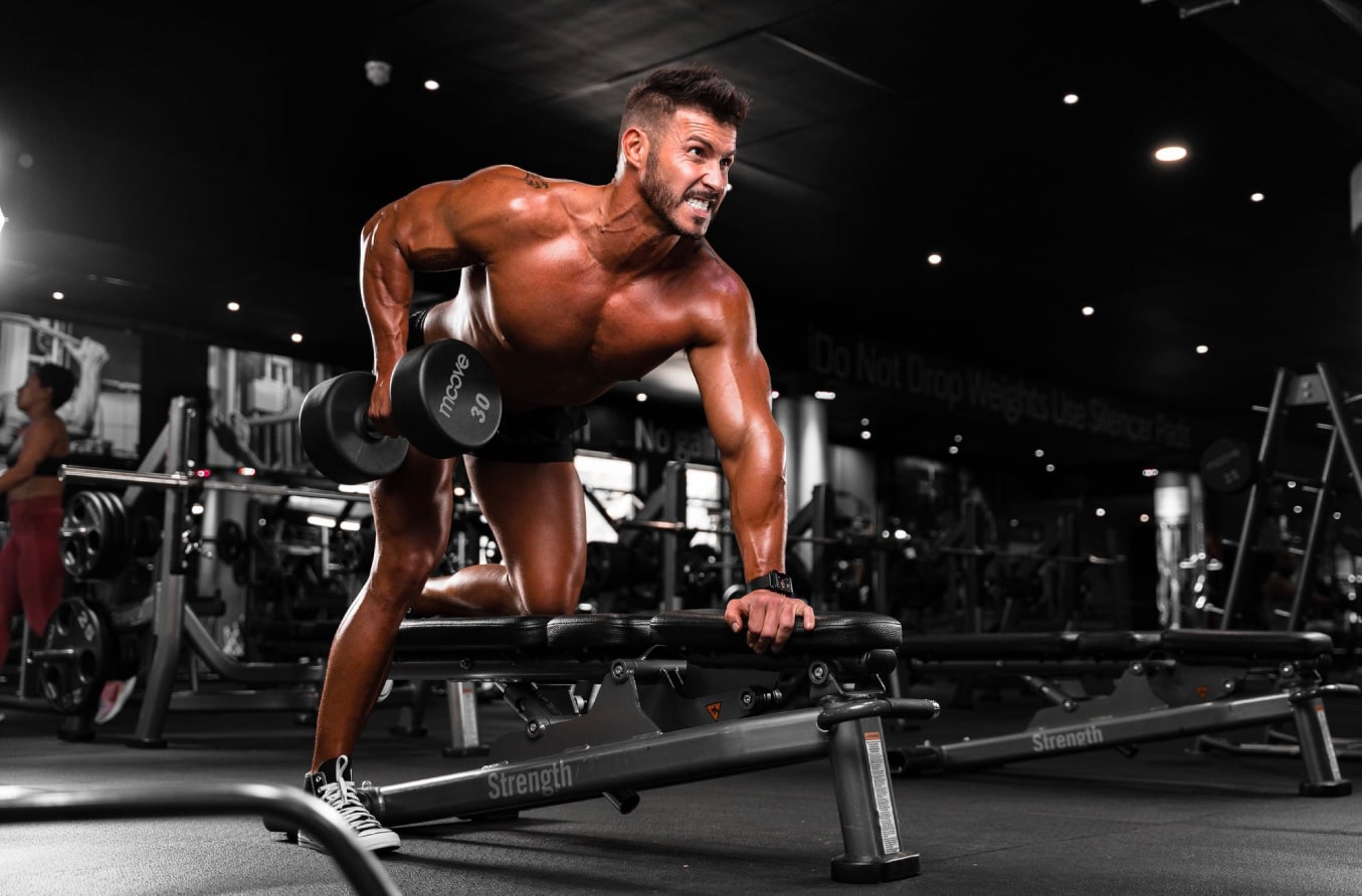 fit young man training single arm dumbell row in the gym
