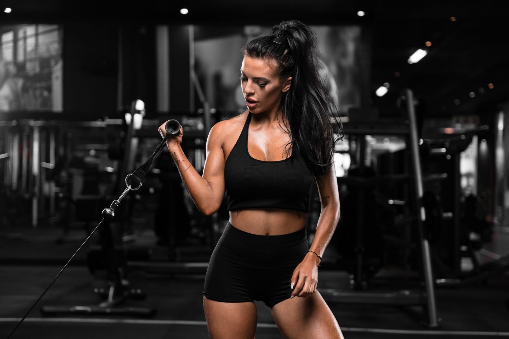 Fit female in black sports bra and shorts doing bicep curl